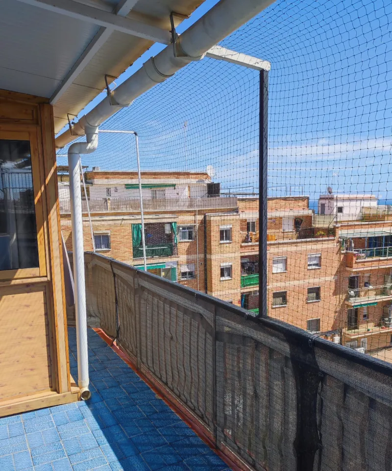 Fotografía de un balcon en Barcelona que tiene una malla de seguridad instalado para que no se escapen los gatos del habitaculo.
